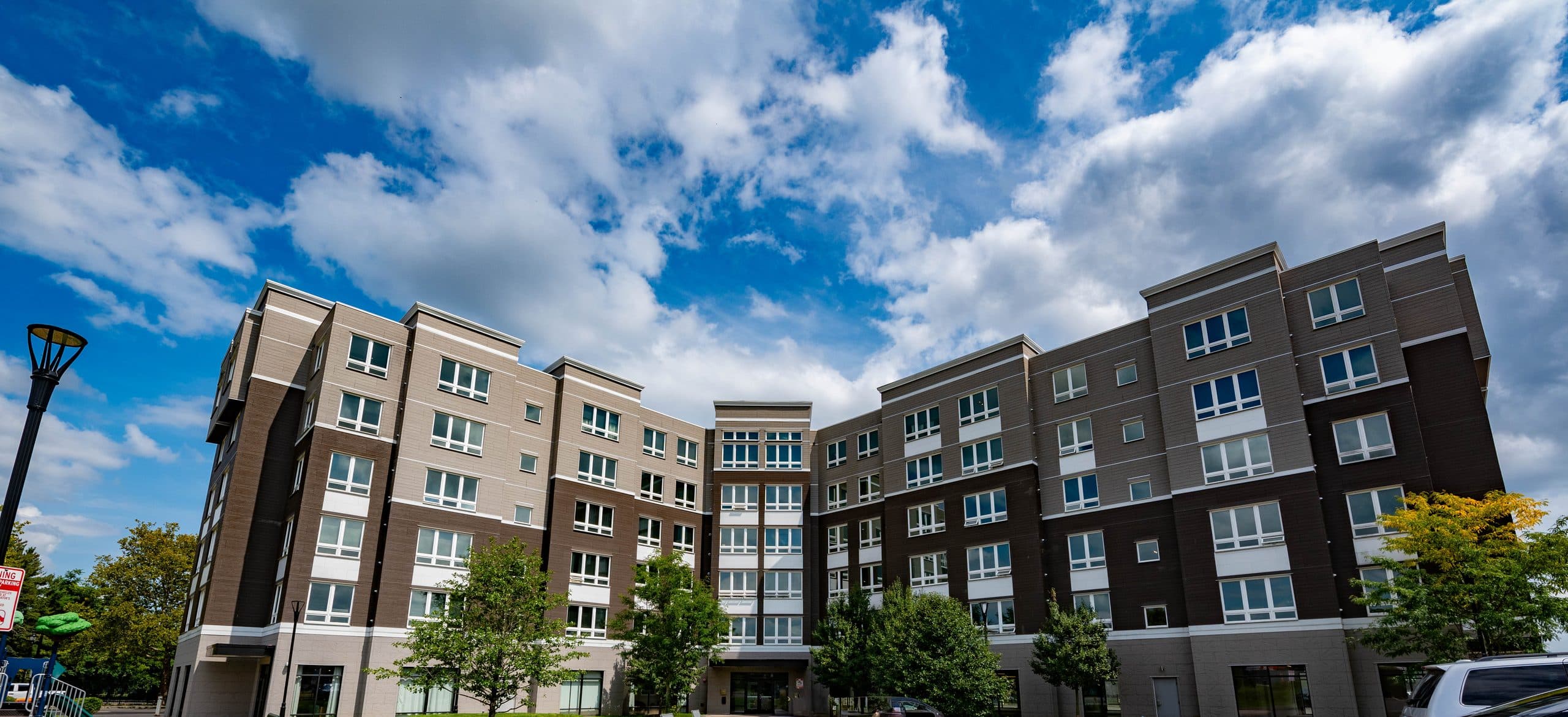 Columbus Commons — a six-storey apartment building in charcoal and grey masonry under a bright summer sky