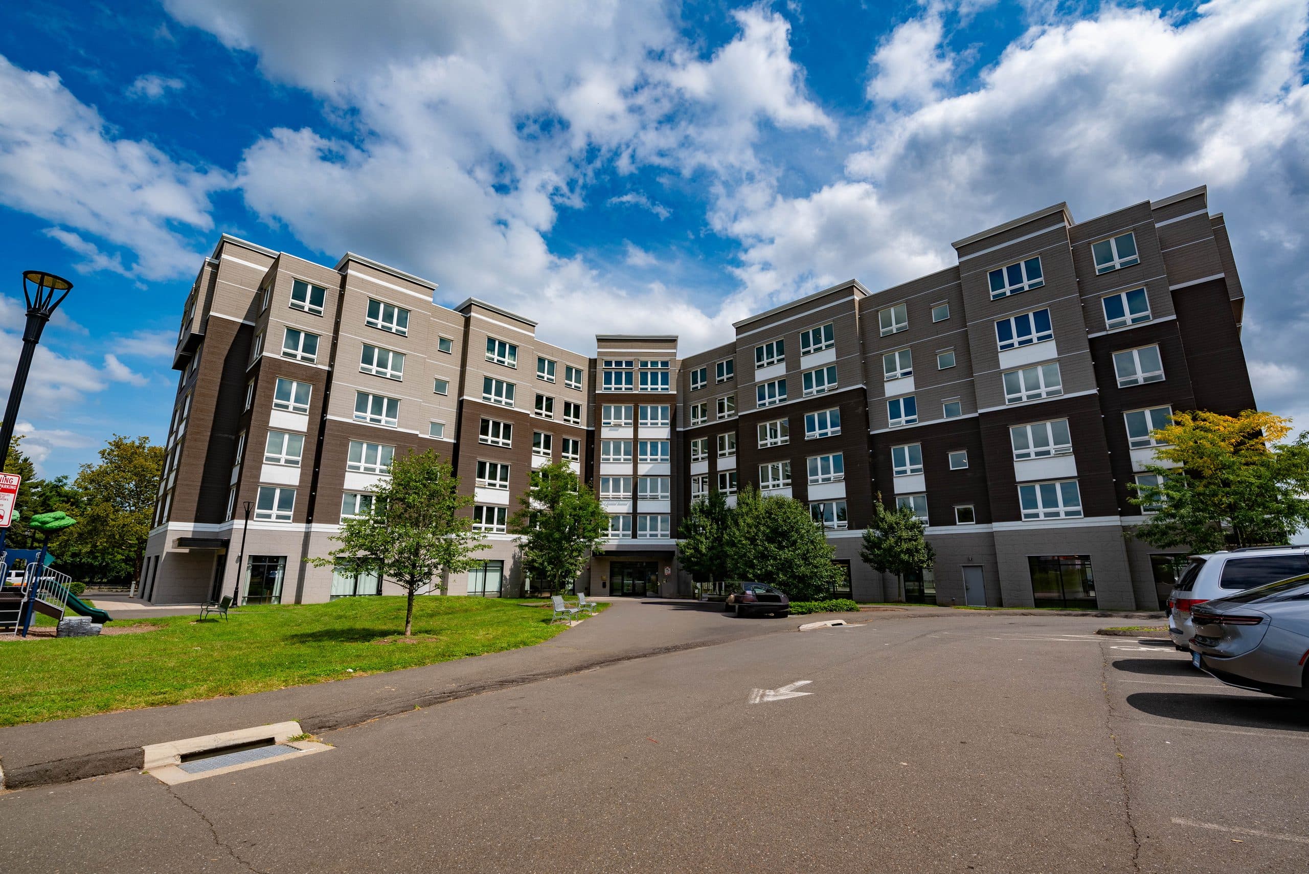 The full front elevation of Columbus Commons, a six-storey building in grey and charcoal masonry under a bright sky